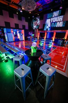 a table with stools in front of it and neon lights on the wall behind it