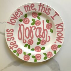 a white plate with pink and green flowers on it that says, loves me this i do not know