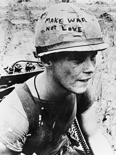 a man wearing a helmet with writing on it sitting in the sand next to a machine