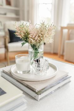 a glass vase filled with flowers sitting on top of a white plate next to a candle