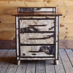 an old wooden dresser with four drawers on it's sides, against a wood paneled wall