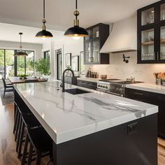 a large kitchen with black cabinets and white counter tops, along with an island in the middle