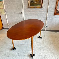 a wooden table sitting in the middle of a room with pictures on the wall behind it