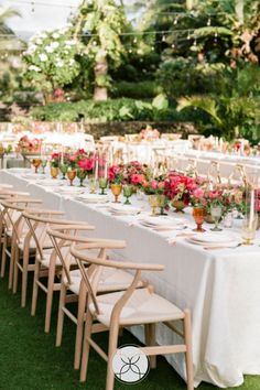 a long table is set up with white linens and gold place settings for an outdoor dinner