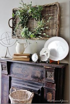 an old fireplace is decorated with greenery and plates