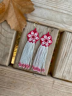 two white and red tassels with flowers on them sitting on a wooden bench