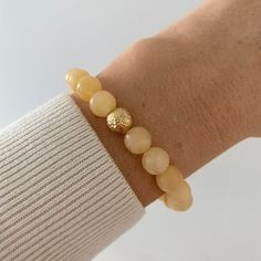 A 24ct gold plated brass pearl with a rustic surface is hidden among the pastel yellow minerals of the Honey Calcite Bracelet, giving it a special overall effect. In addition to the pleasant harmony of colors, honey calcite offers benefits such as energizing and boosting self-confidence.  The bracelet consists of 22 pearls, and thanks to its flexible design, it fits perfectly on an average female wrist.  The bracelet is handmade in our Budapest studio. MATERIAL: 24 carat gold-plated brass, honey Gold Faceted Beaded Bracelets For Everyday, Elegant Amber Beaded Bracelets With Natural Stones, Handmade Adjustable Yellow Gold Pearl Bracelet, Adjustable Handmade Yellow Gold Pearl Bracelet, Elegant Amber Beaded Bracelets, Elegant Hand-strung Amber Bracelets, Elegant Hand-strung Amber Bracelet, Gold Bracelets With Natural Round Beads, Gold Bohemian Pearl Bracelet With Gemstone Beads