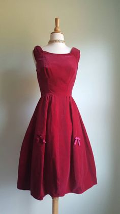 A vintage red: This stunning violet-red velvet 1950s party dress just gets better with time. Gown features a built-in net crinoline and structured interfacing in the skirt for fullness; gathered little cap sleeves; darling satin bows all around, a festive textural contrast to the velvet; and a flattering fitted, princess-seamed bodice. Back metal zip. Era: 1950s Label: No maker tag; there is a custom-order tag Bust: 34/35 inches Waist: 24/25 inches Length from shoulder to hem: 41 inches Vintage Burgundy Dress For Evening, Vintage Burgundy Evening Dress, Burgundy Vintage Evening Dress, 1950s Red Party Dress, 1950s Style Red Party Dress, Vintage Burgundy Party Dress, Red Party Dress, 1950s Party Dresses, 1950s Party