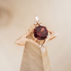 a close up view of a ring with a red stone and white diamonds on it