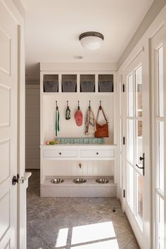 a kitchen with white cabinets and counter tops next to open doors that lead into another room