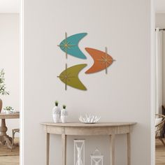 three colorful umbrellas are hanging on the wall above a table in a dining room