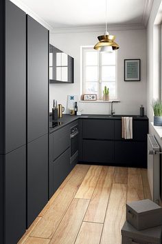 a kitchen with black cabinets and white walls, wood floors and a gold pendant light hanging over the sink