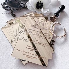 the wedding stationery is laid out on the floor with flowers and jewelry around it