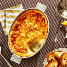 a casserole dish on a table with other dishes and utensils next to it