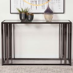 a black console table with two vases on it and a painting above the table