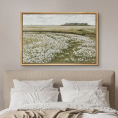 a painting hanging above a bed with white linens and pillows on top of it