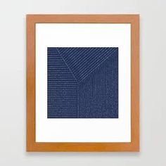 a framed art print with lines in blue and white on the wall above it is a wooden frame