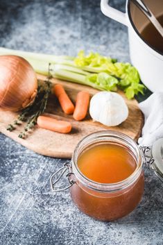 a jar of liquid next to some vegetables on a cutting board