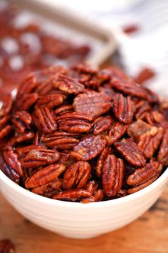 a white bowl filled with pecans sitting on top of a wooden table