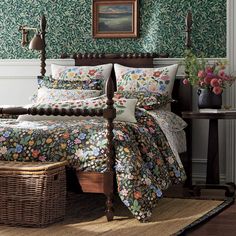 a bedroom with green wallpaper and floral bedding