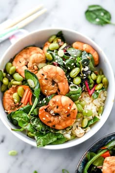 a bowl filled with shrimp and vegetables next to chopsticks on a table top