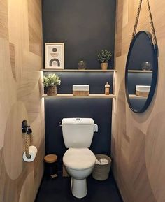 a small bathroom with wood paneled walls and a round mirror above the toilet seat