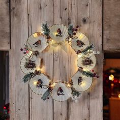 a wreath made out of plates with lights on it and pine cones in the center