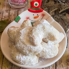 powdered sugar donuts on a white plate with a snowman decoration in the background