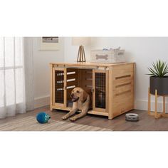 a dog laying on the floor in front of a wooden crate with its door open