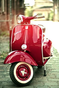 a red scooter is parked on the sidewalk