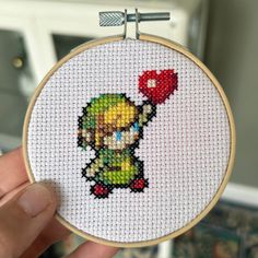 someone is holding up a cross - stitched mario kart character with a red heart