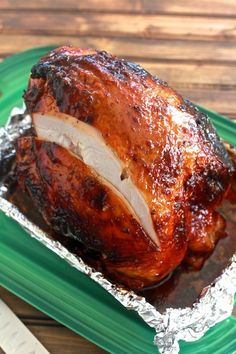 a roasted turkey in foil on a green plate