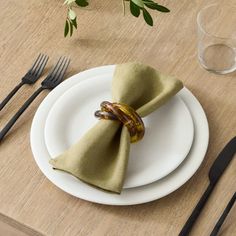 a white plate topped with a napkin and two rings on top of it next to silverware