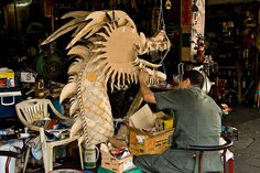 a man sitting in front of a dragon sculpture on top of a wooden table next to other items