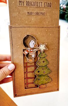 someone is holding up a christmas card with a little boy climbing the ladder in front of a tree