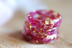 two pink rings with gold flecks sitting on top of a wooden table next to each other