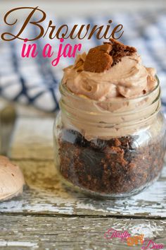 a jar filled with brownie in a jar on top of a wooden table next to a spoon