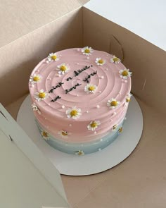 a pink birthday cake with daisies on top in a box for someone's special occasion