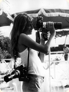 a black and white photo of a woman holding a camera