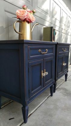 a blue sideboard with gold handles and flowers in a brass vase on the top