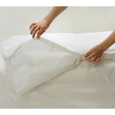 a person unpacking a mattress on top of a white sheeted bed cover