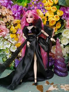 a doll with pink hair and black dress in front of flowers