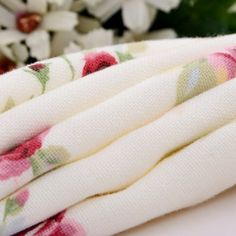 a white towel with pink flowers on it sitting next to a bouquet of daisies