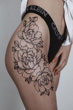 a woman's thigh with black and white flowers on the side, in front of her