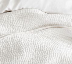 an unmade bed with white sheets and pillows