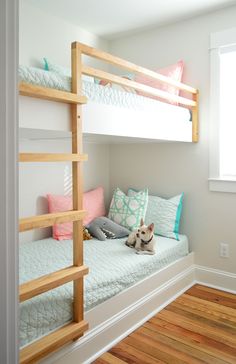 a dog sitting on the bottom bunk of a bed in a room with hardwood floors