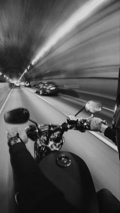 a man riding a motorcycle down a street next to a traffic filled tunnel at night