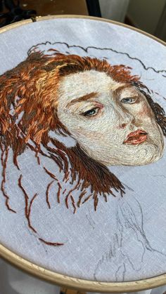 an embroidered portrait of a woman with red hair