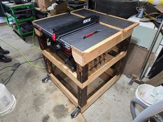 a table sawing on top of some wooden pallets in a garage with other tools