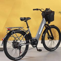 an electric bike parked in front of a yellow wall and potted plant on the floor